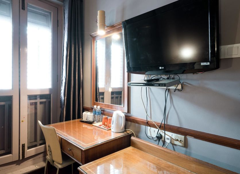 Four Chain View Hotel Singapore room with desk, chair, wall-mounted TV and balcony doors