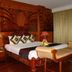 Majestic Oriental Hotel Siem Reap room with carved wood bed, bench and curtain-draped window