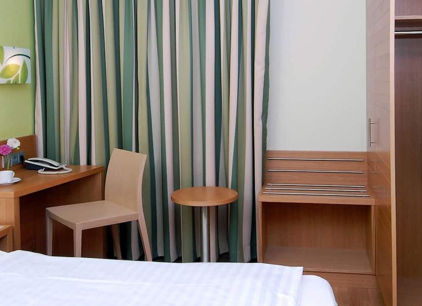 Business & Budget Hotel Tessin Munich guest room with bed, desk, chair and striped curtains