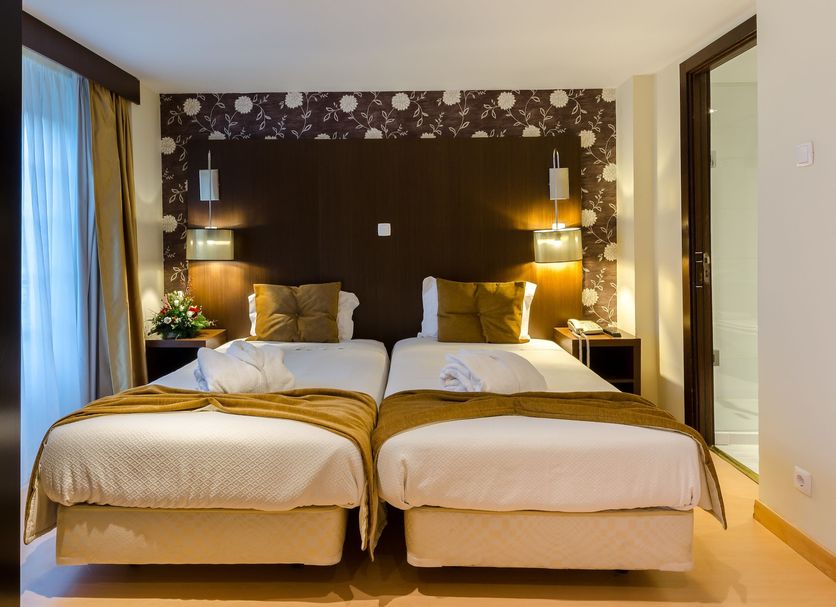 Hotel Duas Nações Lisbon twin bedroom with two single beds, bedside lamps and dark floral accent wall