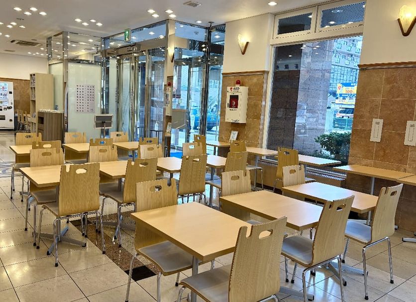 Toyoko Inn Wako-Shi Ekimae in Wako: bright hotel breakfast area with tables, chairs, and vending machines
