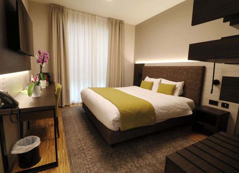 Threeland Hotel Pétange guest room with double bed, desk, window curtains, and modern shelving