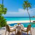 Milaidhoo Maldives infinity pool terrace with ocean view, beach, palm trees and dining table in Kamadhoo