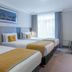 Maldron Hotel Dublin Airport in Dublin: bright triple room with three beds, desk and yellow chair