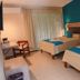 Hotel Plaza Palenque guest room with two twin beds, teal accent wall, and balcony curtains in Palenque