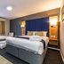 Days Inn by Wyndham London Stansted Airport room with double bed, single bed, window, and seating area