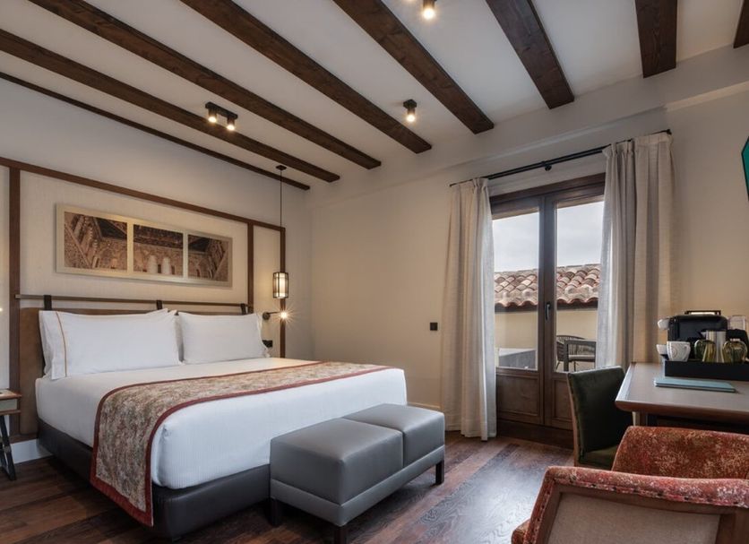 Áurea Toledo by Eurostars Hotel company guest room with king bed, bench, and balcony doors in Toledo