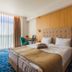 Marina Burgas Hotel in Burgas guest room with tufted bed, floor-to-ceiling window and blue patterned carpet