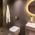Zedwell Piccadilly Circus London bathroom with wall-mounted toilet, glass shower and round lit mirror