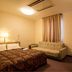 Hotel Ikedaya, Matsumoto guest room with bed, sofa, desk, TV and window curtains