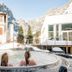 Therme 51 in Leukerbad with guests in an outdoor hot tub overlooking snowy alpine mountains