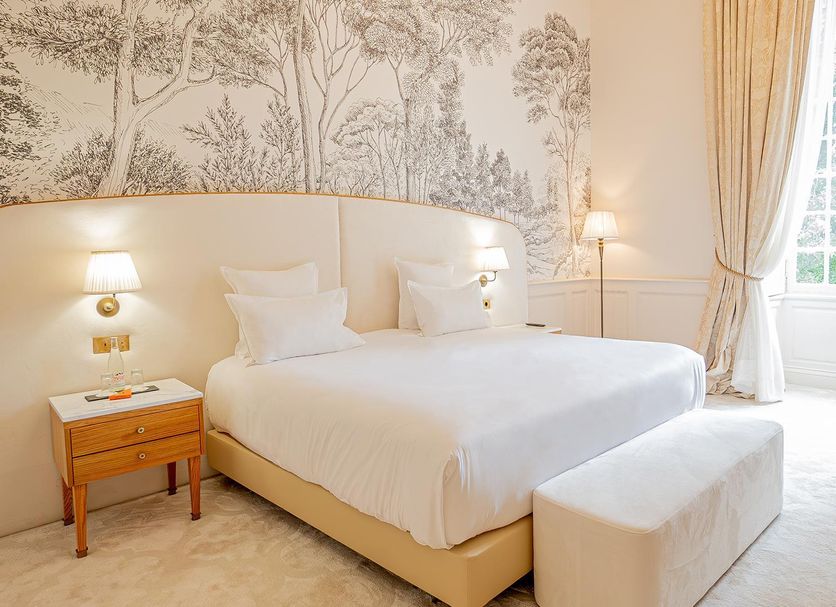 Château De Noirieux, Briollay: elegant bedroom with king bed, toile wallpaper, and tall window with drapes