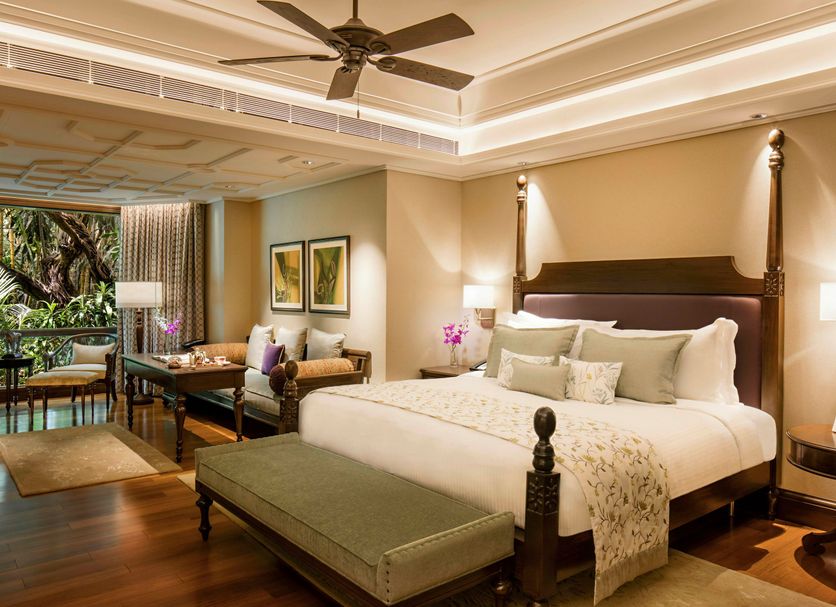 Taj West End Bengaluru bedroom with four-poster bed, sitting area, and balcony view in Bengaluru
