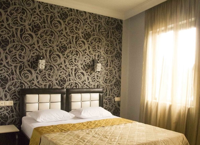 Hotel Iberia Batumi guest room with double bed, patterned accent wall and bright window