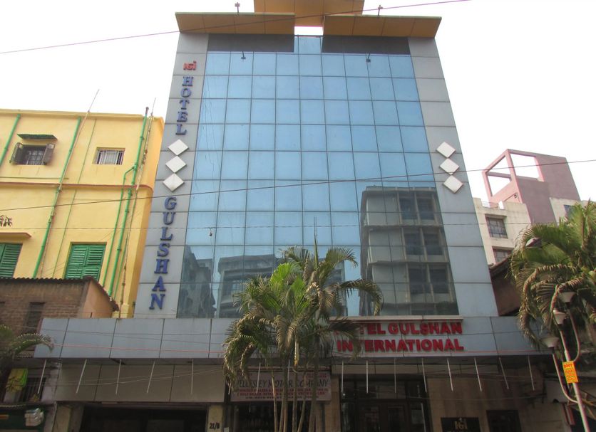 Hotel Gulshan International in Kolkata with a glass-front exterior and palm trees at the entrance