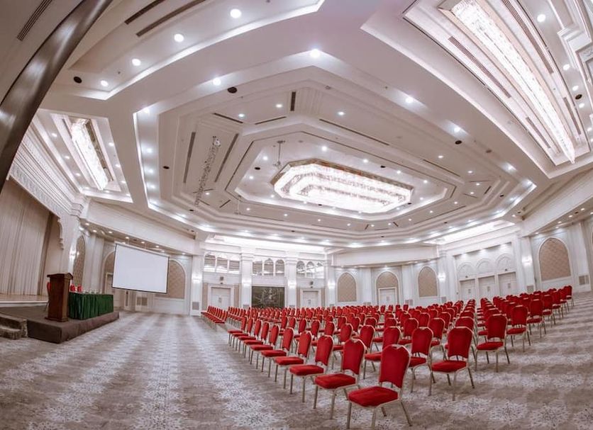 Azimut Grand Hotel Tashkent ballroom in Tashkent with rows of red chairs and ornate ceiling