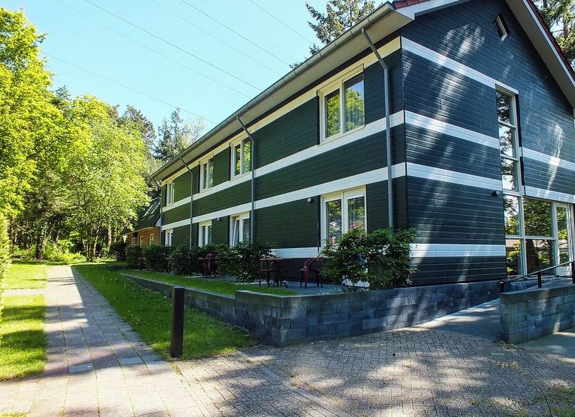 Hotel de Stoppelberg in Beekbergen, exterior of a green two-story lodge-style building surrounded by trees