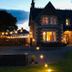 Lairds Lodge Inverness in Inverness, lit stone lodge exterior at dusk with garden lights