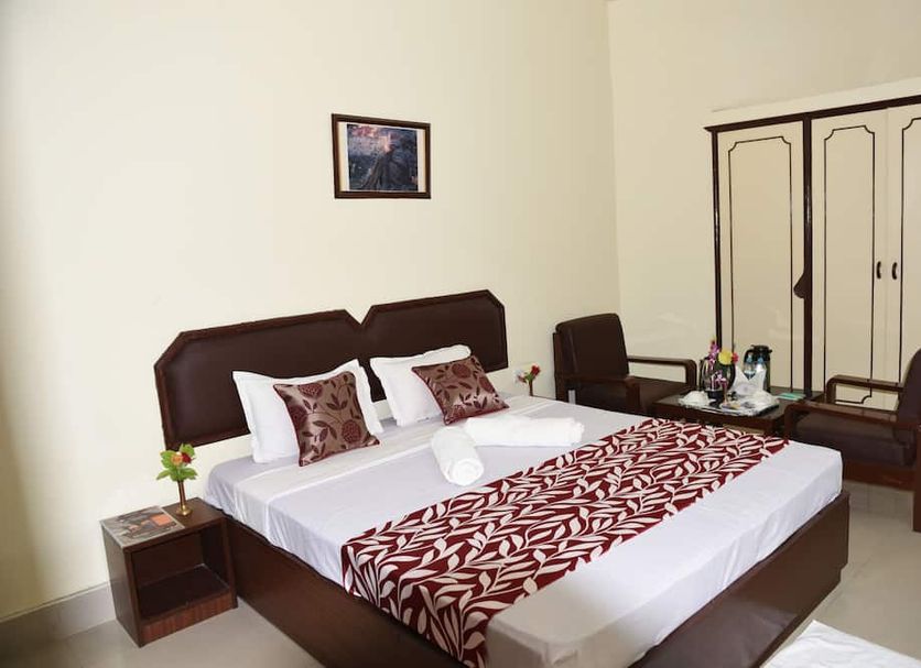 Hotel Lumbini International, Bodh Gaya: double bed with patterned runner, chairs, and wardrobe in guest room