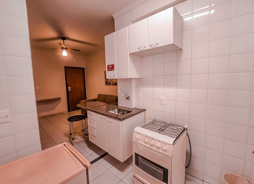 Pampulha Flat Belo Horizonte kitchenette with stove, countertop, cabinets and small dining area