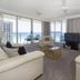 Sunbird Beach Resort Main Beach living room with ocean-view windows and balcony