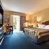 Trianon Bonita Bay Hotel in Bonita Springs guest room with king bed, desk, and balcony door