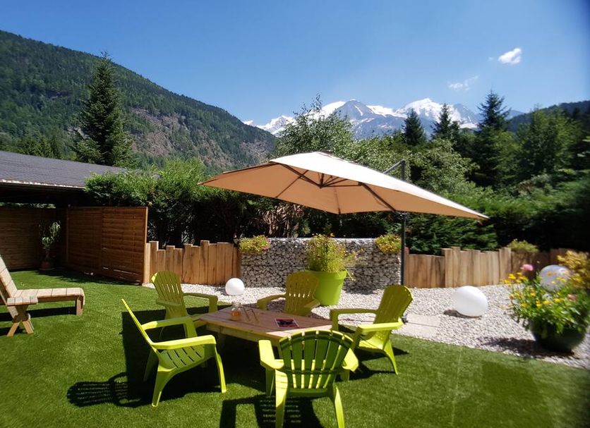 Hotel La Fontaine in Les Houches: mountain-view garden terrace with lime-green chairs and umbrella