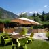 Hotel La Fontaine in Les Houches: mountain-view garden terrace with lime-green chairs and umbrella