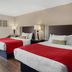 SureStay by Best Western Greenville room with two double beds, red bed runners, lamps, and window curtains.
