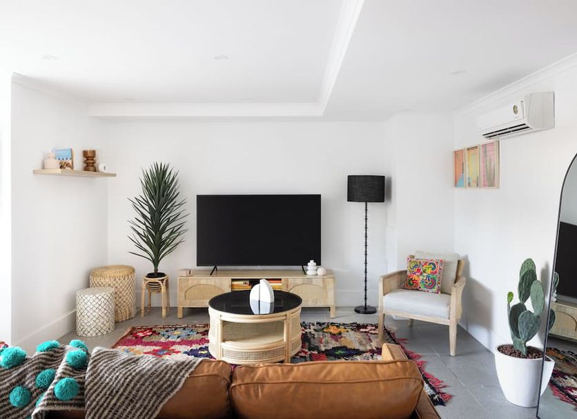 Hotel Hacienda Sydney lounge with TV, colorful rug, armchair, and arched mirror in a bright room