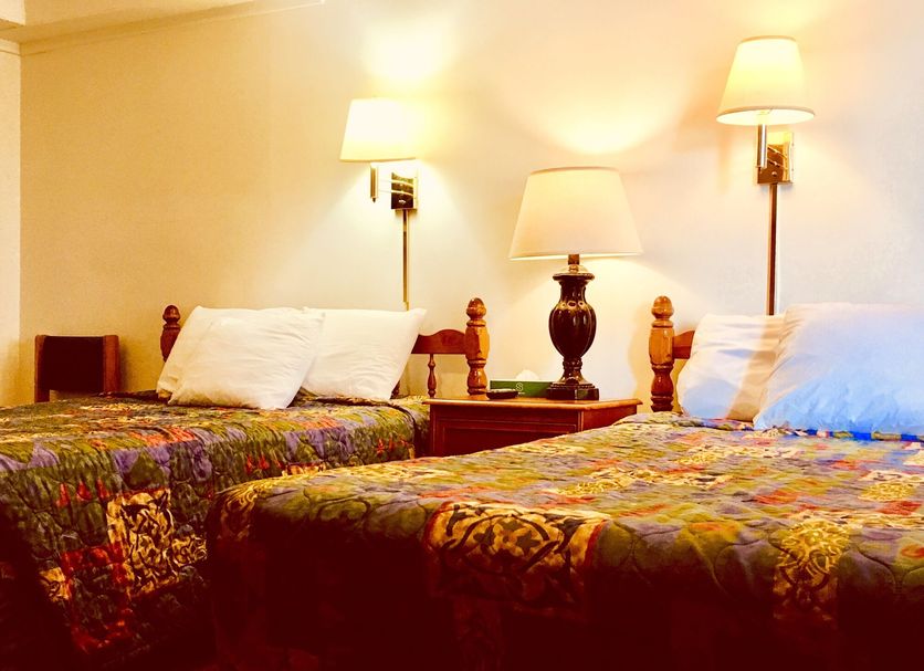 North Country American Inn in Kalkaska guest room with two double beds and wall lamps