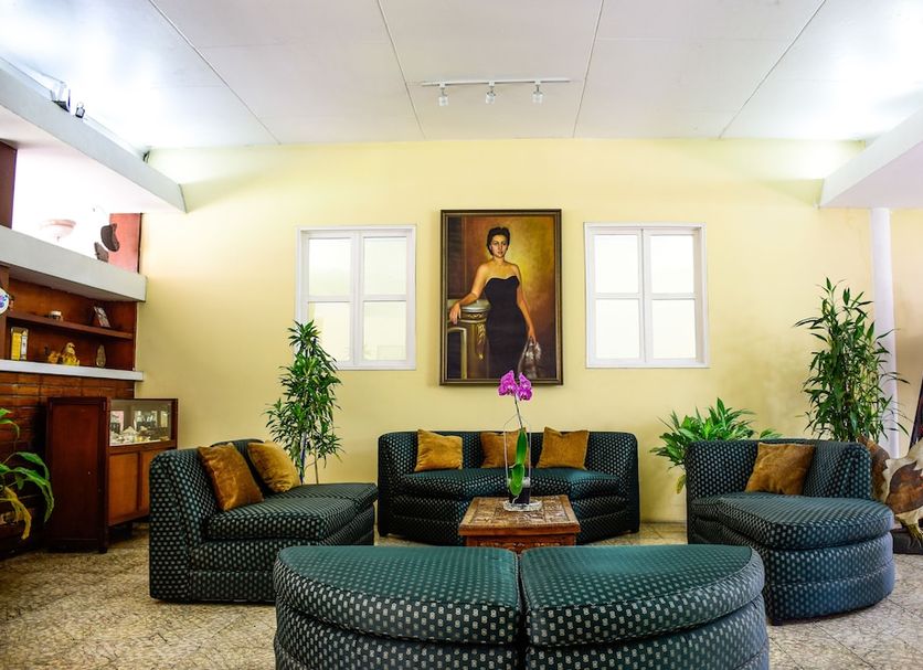 Eco Hotel Mariscal in San Salvador lobby with green seating, potted plants and framed portrait