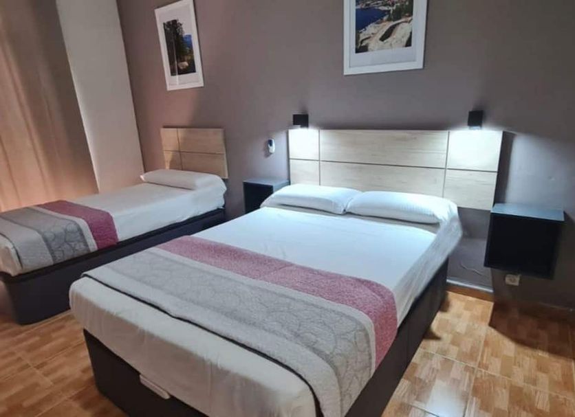Hostal Miami in Madrid guest room with two single beds, bedside lamps, and wood parquet flooring.