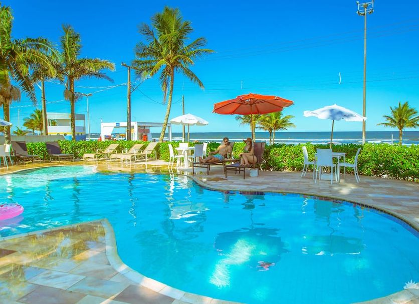 Hotel Villareal Guaratuba - Caieiras pool with ocean view, palm trees and lounge chairs in Guaratuba