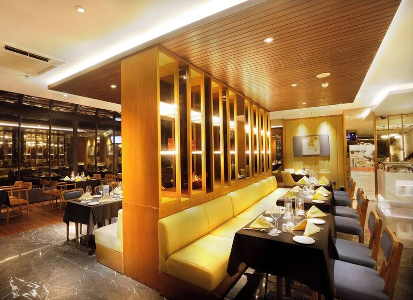 Swiss-belhotel Pondok Indah Jakarta dining room with yellow banquette seating and set tables