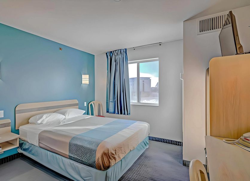 Econo Lodge Menomonie guest room with a bed, blue accent wall, and window view in Menomonie