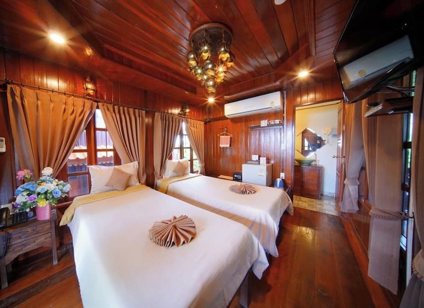 Pludhaya Resort & Spa in Ayutthaya: wood-paneled twin bedroom with canopy beds and warm lighting