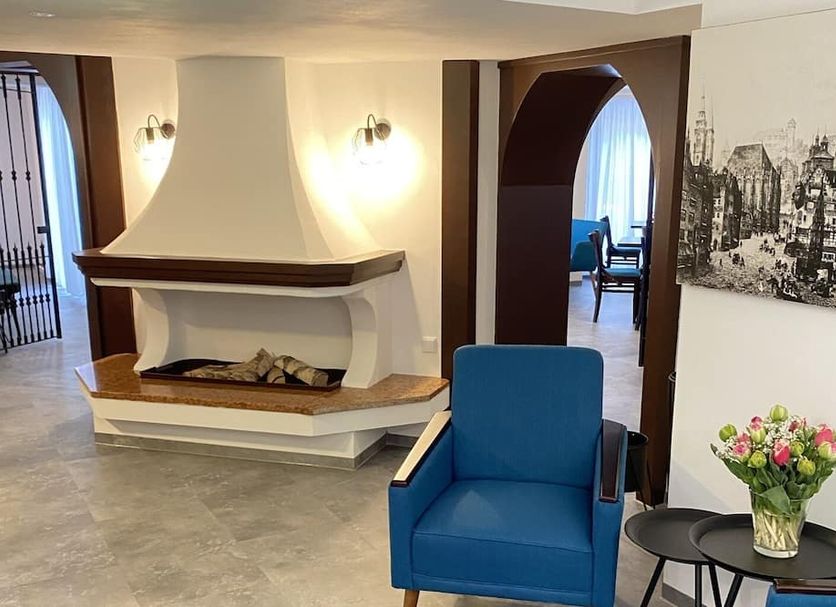 Burghotel Nürnberg in Nuremberg: lounge with fireplace, blue armchair, archway and flower vase