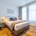 The Grosvenor in Timaru guest room with king bed, teal chair, desk and sheer curtains