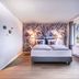 Steigenberger Hotel Treudelberg Hamburg room with king bed, floral accent wall and large windows
