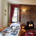 Glenan Lodge Self Catering in Inverness dining room with stone fireplace, set tables and red curtains