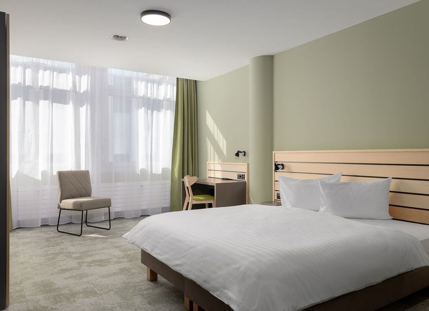 flexymotel Buchs guest room with double bed, desk, chair, and large window in Buchs