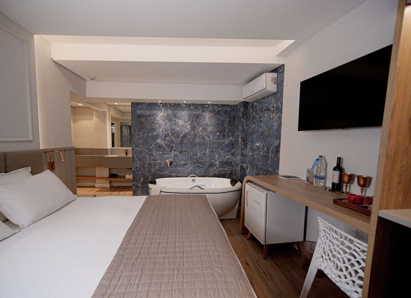 Hotel Marimar The Place in Balneário Camboriú room with bed, bathtub, wall TV and desk