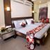 Hotel NavaRATNA Coimbatore guest room with king bed, bedside tables, curtains, and wall-mounted TV
