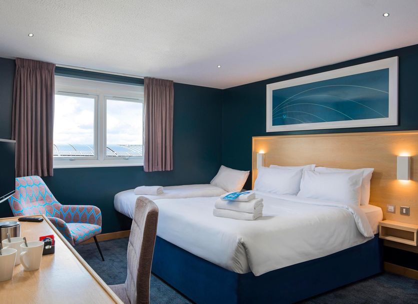 Travelodge Dartford room with twin beds, window view and teal walls in Dartford