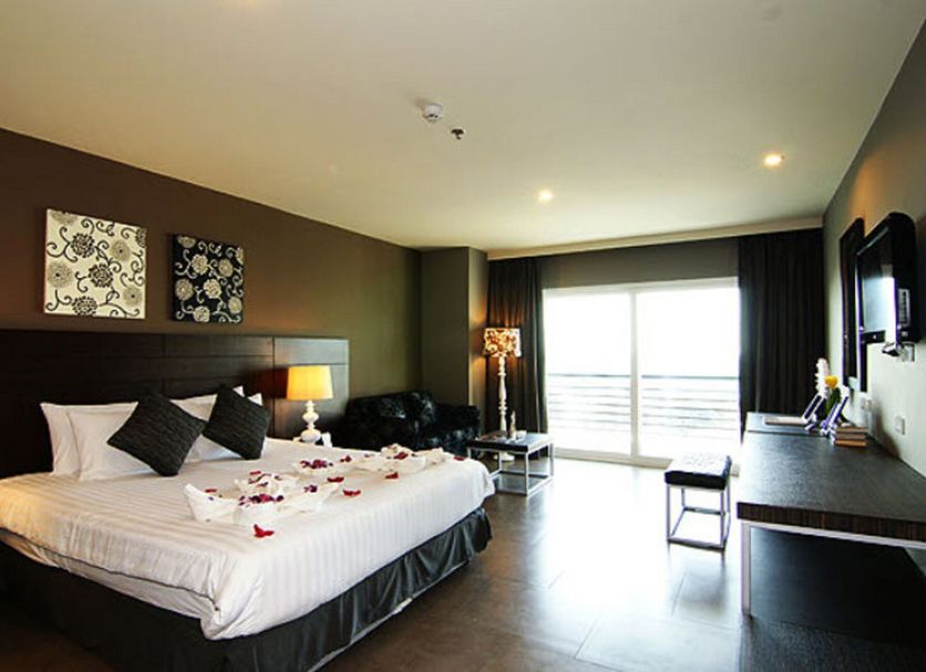 Sea Me Spring Hotel Pattaya guest room with bed, sofa, desk and balcony doors