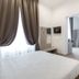 Apollo Guest House in Florence guest room with double bed, wardrobe, vanity desk and curtain-draped window