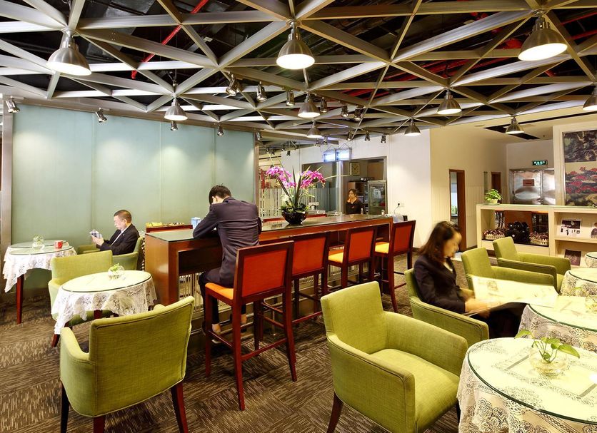 Yanjiang East Garden Inn in Guangzhou lounge with bar seating, green armchairs and café tables