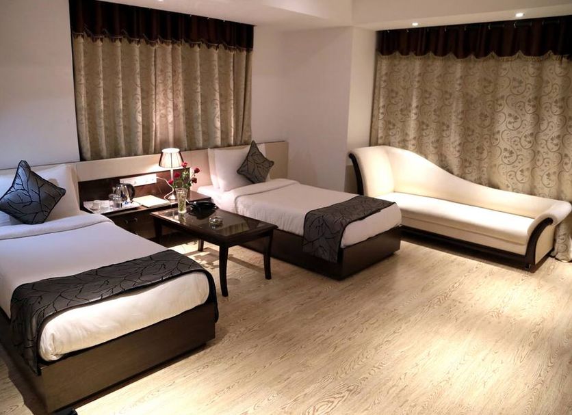 The Grand Radiant Hotel in Lucknow room with two beds, chaise lounge, and coffee table