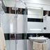 Hotel Mediterraneo in Porto Cesareo bathroom with curved glass shower, sink, mirror and towel.